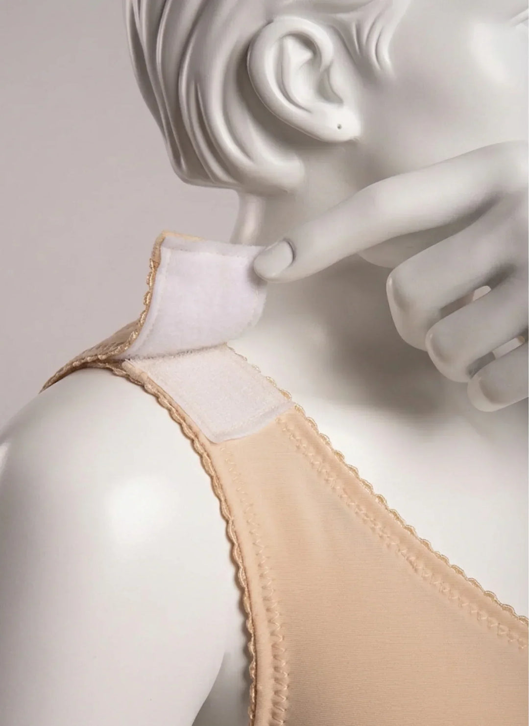 Beige compression vest with adjustable shoulder strap on mannequin, close-up view